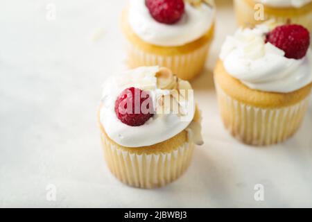 Nahaufnahme. Appetitliche Muffins mit Rahm, Himbeeren und Mandeln. Isoliert auf weißem Hintergrund. Süßwaren, Restaurant, Hotel, kulinarischer Blog. Adver Stockfoto
