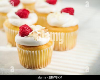 Nahaufnahme. Muffins mit Schlagsahne, Himbeeren und Mandeln. Isoliert auf weißem Hintergrund. Auf dem Foto befinden sich keine Personen. Süßes Essen, Kalorien. B Stockfoto