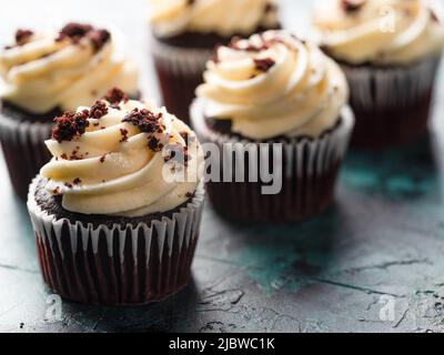 Schokoladen-Cupcakes mit Schlagsahne und geriebener Schokolade. Viele Objekte. Feiertag, Geburtstag, Bankett. Restaurant, Hotel, Café, Konditorei, Stockfoto