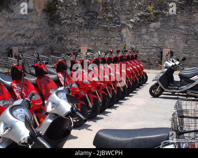 Roller standen auf dem Parkplatz der Royal Navy Dockyard auf der Insel Bermuda an. Die Motorroller warten auf die Vermietung von Touristen für Ausflüge rund um die Insel. Stockfoto