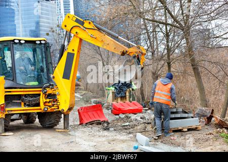 Eine Gruppe von Bauarbeitern entladen Betonkanten mit einem Bagger, um einen Gehweg zu bauen. Stockfoto