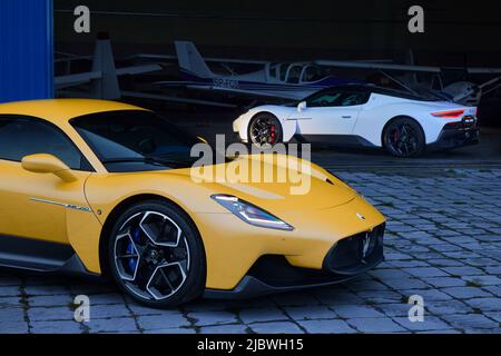 Maserati MC20 steht im Flugzeughangar und gelb MC20 parkt vor dem Hangar. Katowice, Polen, 23.09.2021 Stockfoto