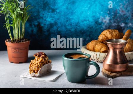 Gebrauter schwarzer Kaffee in einer Kupferkessel. Kaffee in Tassen und Süßigkeiten aus Nüssen. Kaffee wird serviert. Stockfoto