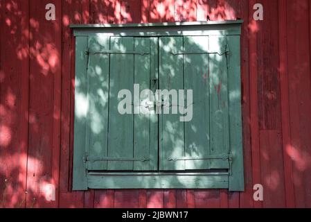 Rote Holzhauswand mit grünen Fensterläden Stockfoto