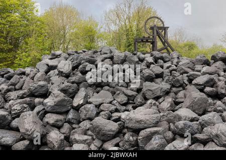 Kohlestapel mit altem Bergbaurad im Hintergrund Stockfoto