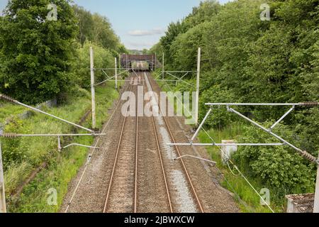 Die Gleise fahren bis zur Entfernung, auf der die von oben aufgenommenen Oberleitungsanlagen angezeigt werden Stockfoto