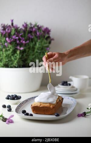 Frau, die den gebumpften Kuchen mit Glasur dekoriert, Nahaufnahme der Hand, die den Kuchen schmückt. Stockfoto