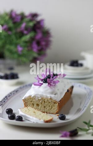 Gebündelter Kuchen mit Verglasung, dekoriert mit frischen Heidelbeerfrüchten und Lavendelblüten. Stockfoto