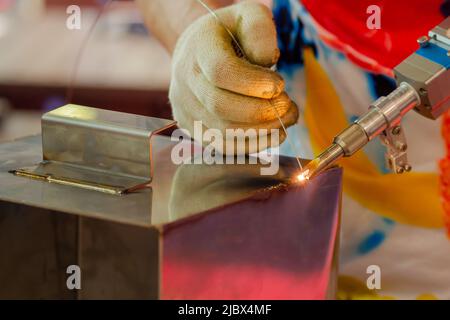 Schweißer Hände mit einem tragbaren Laserschweißgerät - Nahaufnahme Stockfoto