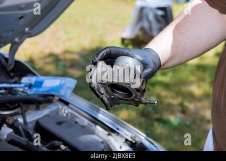 Hand A Mann halten Drosselklappe im Auto Service Motor Drosselklappe Austausch Stockfoto