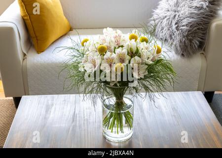 Craspedia und Alstroemeria Blumen in einer Vase auf einem Couchtisch Stockfoto