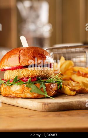 Großer Cheeseburger mit pommes frites. Hamburger mit Rinderfilet, Tomaten, Salateingelegter, geschmolzenem Cheddar, Senf, Tomatenmarmelade, Mayo. Stockfoto