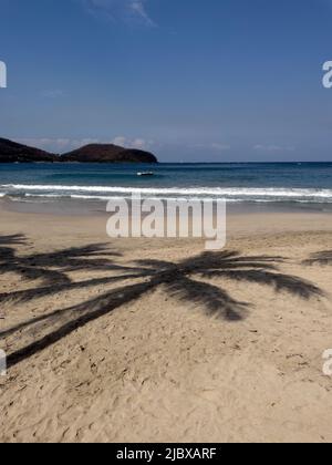Schatten von Palmen am Sandstrand von La Playa Ropa in Zihuatanejo, Mexiko Stockfoto