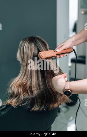 Nahaufnahme ziehen Strähnen mit professionellen Ultraschall-Eisen-Tool. Wellnessbehandlung. Keratin Richten und Wiederherstellung. Hochwertige Fotos Stockfoto