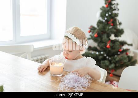 Kindermädchen in weihnachtskleid mit Cochlea-Implantaten gekleidet Spaß zu Hause - Vielfalt und Hörgeräte und innovative Technologien für die Behandlung Stockfoto