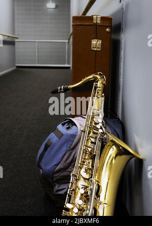 Saxophon lehnt sich im Schulkorridor an den Schulrucksack Stockfoto