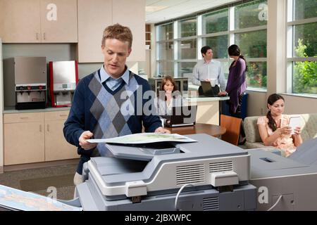 Mann, der im Pausenraum im Büro Kopien einer Karte anfertigte Stockfoto