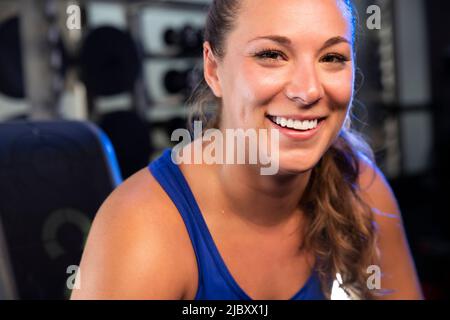 Lächelndes Porträt einer jungen Frau, die in einem Fitnessstudio arbeitet Stockfoto