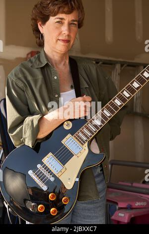 Portrait eines Gitarristen in der Garagenband, bestehend aus Frauen mittleren Alters, die in einer Garage üben Stockfoto