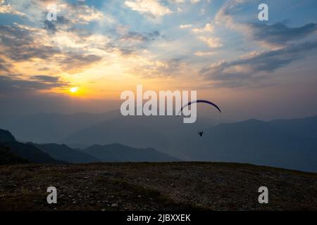 Gleitschirm, der bei Sonnenuntergang in Nepal von der Klippe abfliegt. Stockfoto