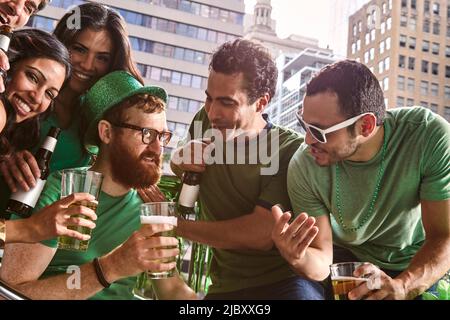 Eine Gruppe verschiedener Freunde rösten beim Bier und feiern den St. Patrick's Day Stockfoto