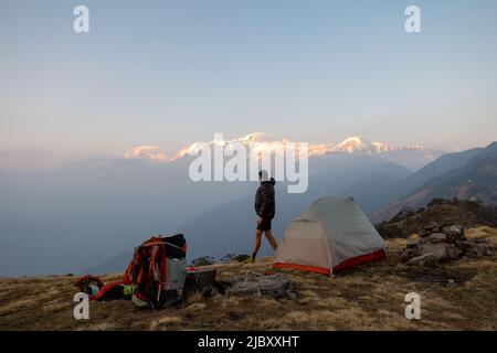 Wanderer bei Sonnenaufgang auf dem Campingplatz mit Blick auf die Berge in der Ferne. Nepal. Stockfoto