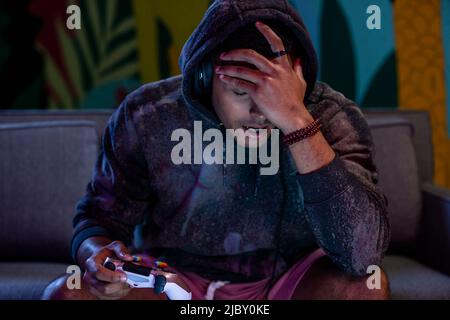 Junge männliche Gamer spielen Videospiel zu Hause und sehen verzweifelt und frustriert aus. Stockfoto