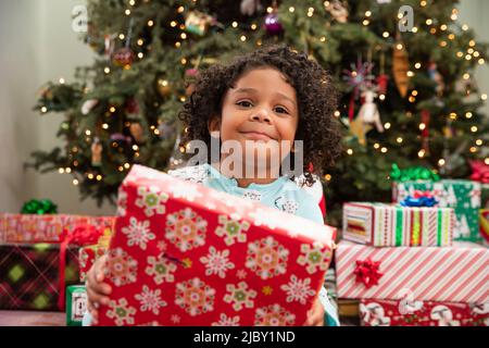 Happy girl Eröffnung ihr Weihnachtsgeschenk mit großen glücklichen Lächeln. Stockfoto