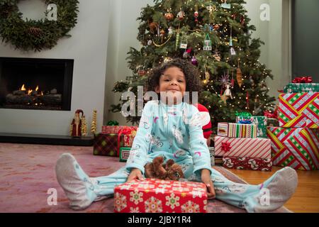 Portrait von überrascht Mädchen halten verpackte Geschenk an Weihnachten Stockfoto