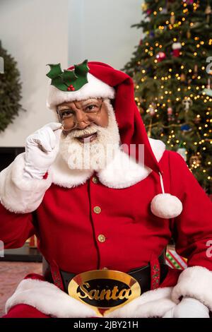 Älterer schwarzer Mann, der als Weihnachtsmann für eine Familienurlaubsfeier gekleidet war. Stockfoto