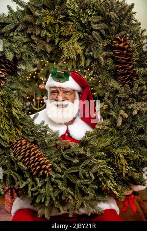 Schwarzer afroamerikanischer Mann im Weihnachtsmann Kostüm lächelt vor der Kamera. Stockfoto