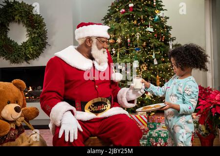 Schüchterner Siebenjähriger, der dem Weihnachtsmann Milch und Kekse überreichte Stockfoto