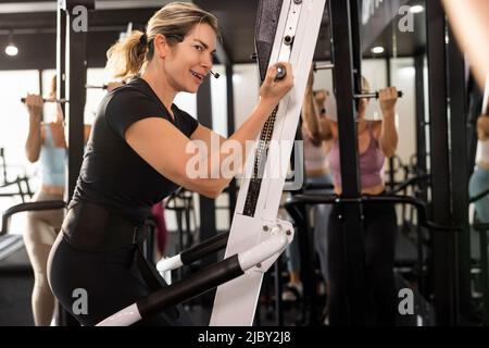 Lächelnde Fitnesstrainerin mit Mikrofon-Headset und Gespräch mit dem Kurs während des Trainings. Stockfoto