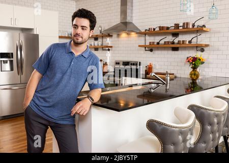 Porträt eines jungen Mannes mit einer coolen Einstellung, der in der Küche steht und von der Kamera schaut. Stockfoto
