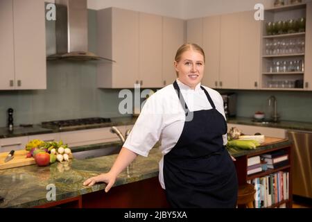 Porträt von Chefkoch Megan Gill in der heimischen Küche beim Blick auf die Kamera Stockfoto