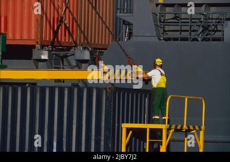 Mann, der Transportbehälter für die Verladung auf dem Schiff sicherte Stockfoto