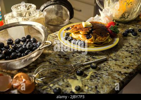 Detail der Platte mit Pfannkuchen mit Obst auf unordentlichen Küchentheke nach der Herstellung Heidelbeer Pfannkuchen Stockfoto