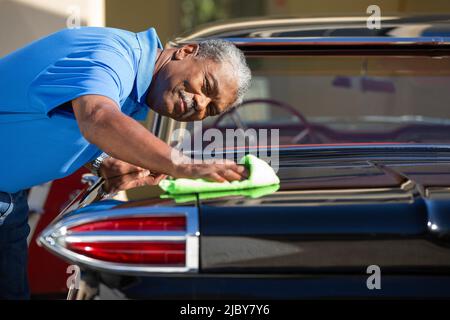 Älterer Mann trocknet alten Oldtimer aus. Stockfoto