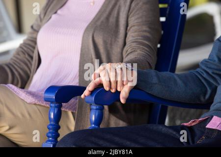 Ein älteres Paar sitzt in Schaukelstühlen, Details über die Hände halten Stockfoto