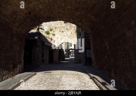 Gepflasterte Gasse mit steinernen Torbögen, in der Altstadt von Rhodos, Insel Rhodos, Griechenland, Dodekanes. Aufgenommen am 2022. Mai. Frühling Stockfoto