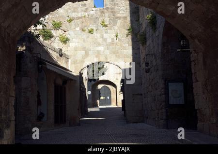 Gepflasterte Gasse mit steinernen Torbögen, in der Altstadt von Rhodos, Insel Rhodos, Griechenland, Dodekanes. Aufgenommen am 2022. Mai. Frühling Stockfoto