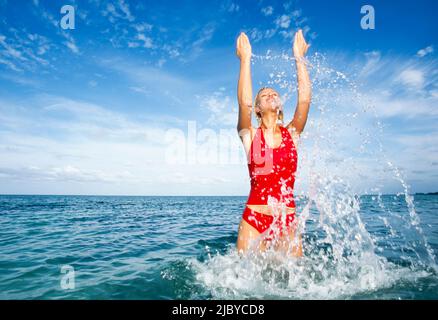 Frau in rotem Badeanzug, die im tropischen Ozean spielt Stockfoto