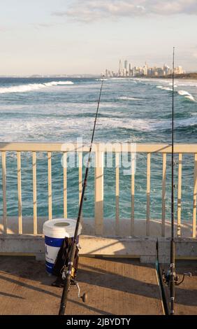 Angelrute, die sich an einem Geländer des permanenten Pontoons lehnt und in Richtung Surfers Paradise - Gold Coast blickt Stockfoto