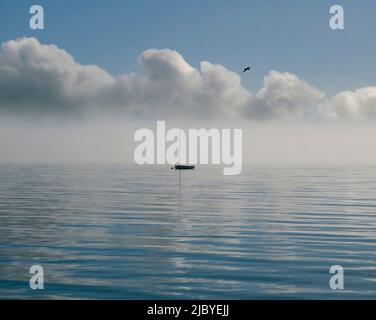 Kleines Boot, das auf plätscherndem blauem Wasser schwimmt, und Meeresnebel rollt hinein Stockfoto