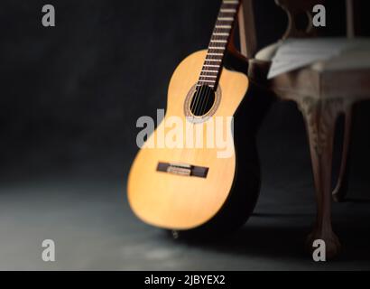 Klassische Gitarre, die mit Noten gegen einen Stuhl gelehnt ist Stockfoto