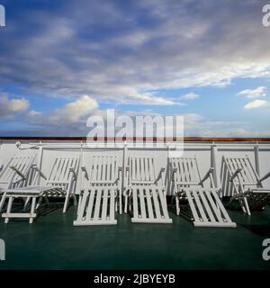 Reihe von weißen Liegestühlen an Deck des Kreuzschiffs Stockfoto