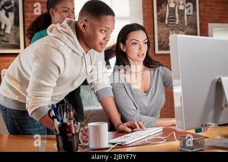 Eine Gruppe junger Mitarbeiter im Büro versammelten sich um den Computerbildschirm Stockfoto