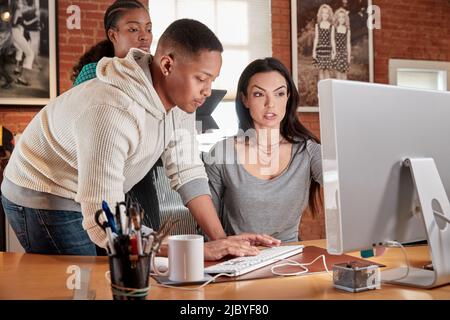 Eine Gruppe junger Mitarbeiter im Büro versammelten sich um den Computerbildschirm Stockfoto