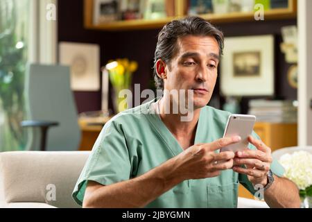 Hispanischer Arzt mit Telemedizin aus seinem Heimbüro, der per Videoanruf mit dem Patienten auf dem Handy spricht Stockfoto