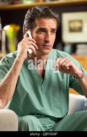 Hispanischer Arzt, der in seinem Büro Telemedizin praktiziert und mit dem Patienten am Handy spricht Stockfoto